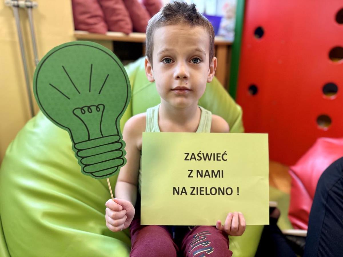 Uczeń trzyma napis "Zaświeć z nami na zielono!"