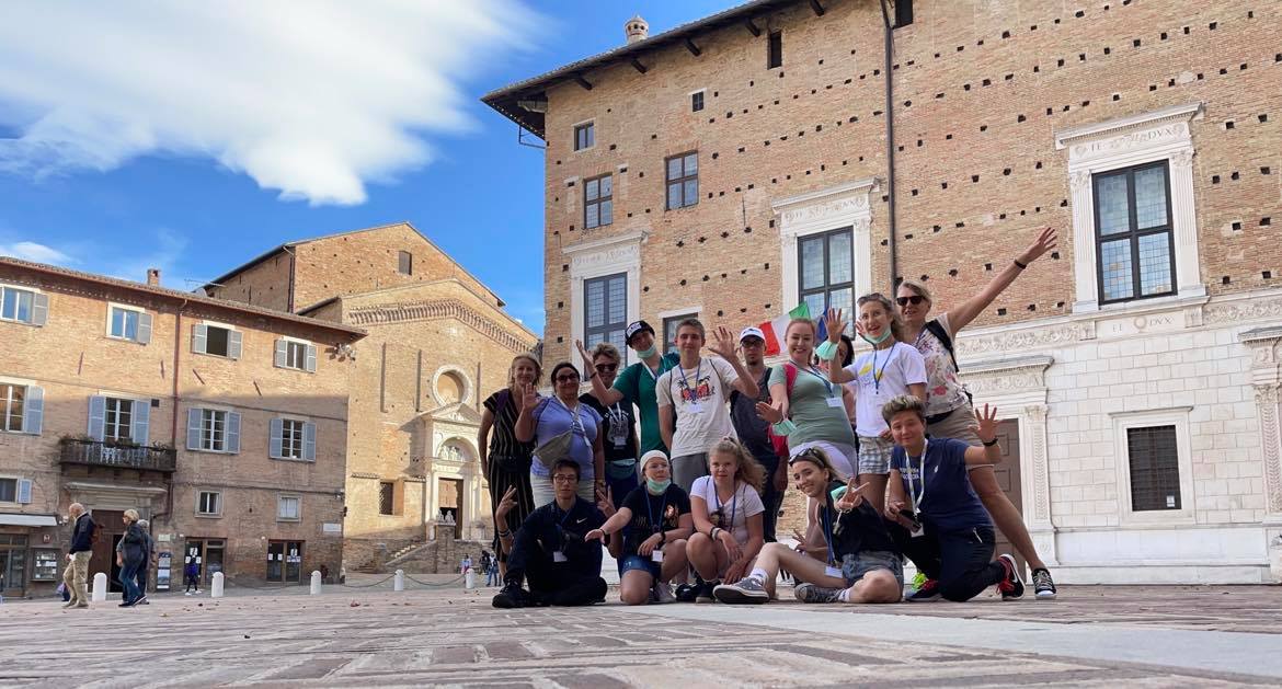 Grupa uczniów i nauczycieli na tle zabytków włoskiego Fano